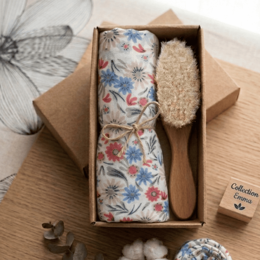 coffret brosse et lange fleuris bleu beige rouge posé sur une table à langer
