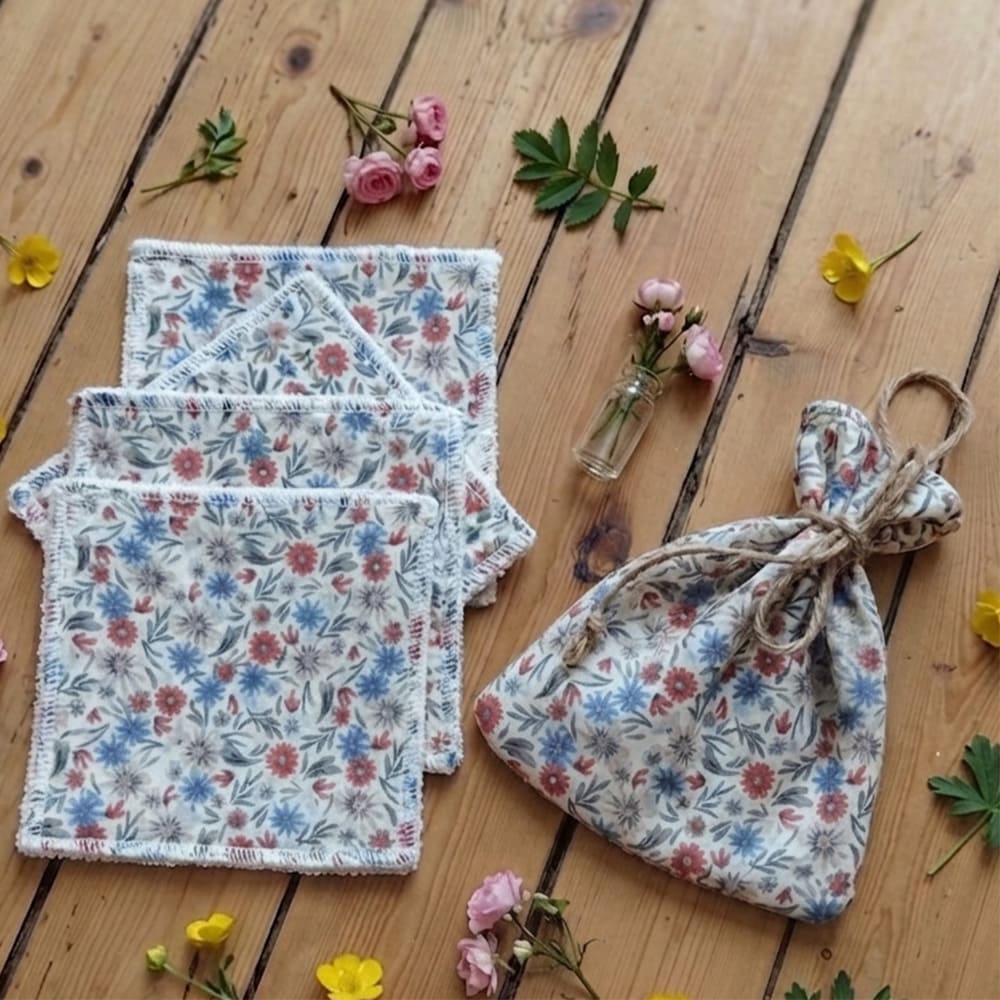 Pochon avec 4 lingettes aux motifs fleuris bleu et rose posé sur une table en bois