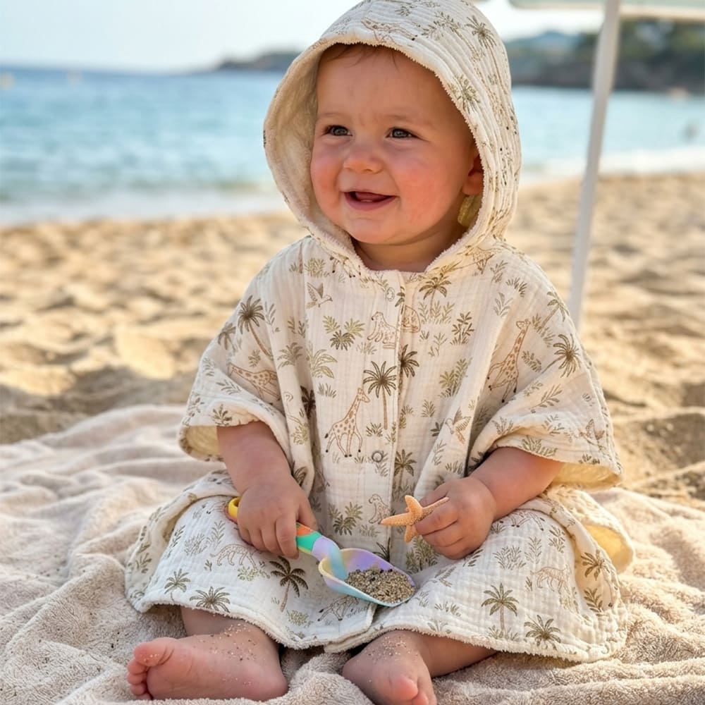 Bébé à la plage dans le poncho de plage au motifs safari