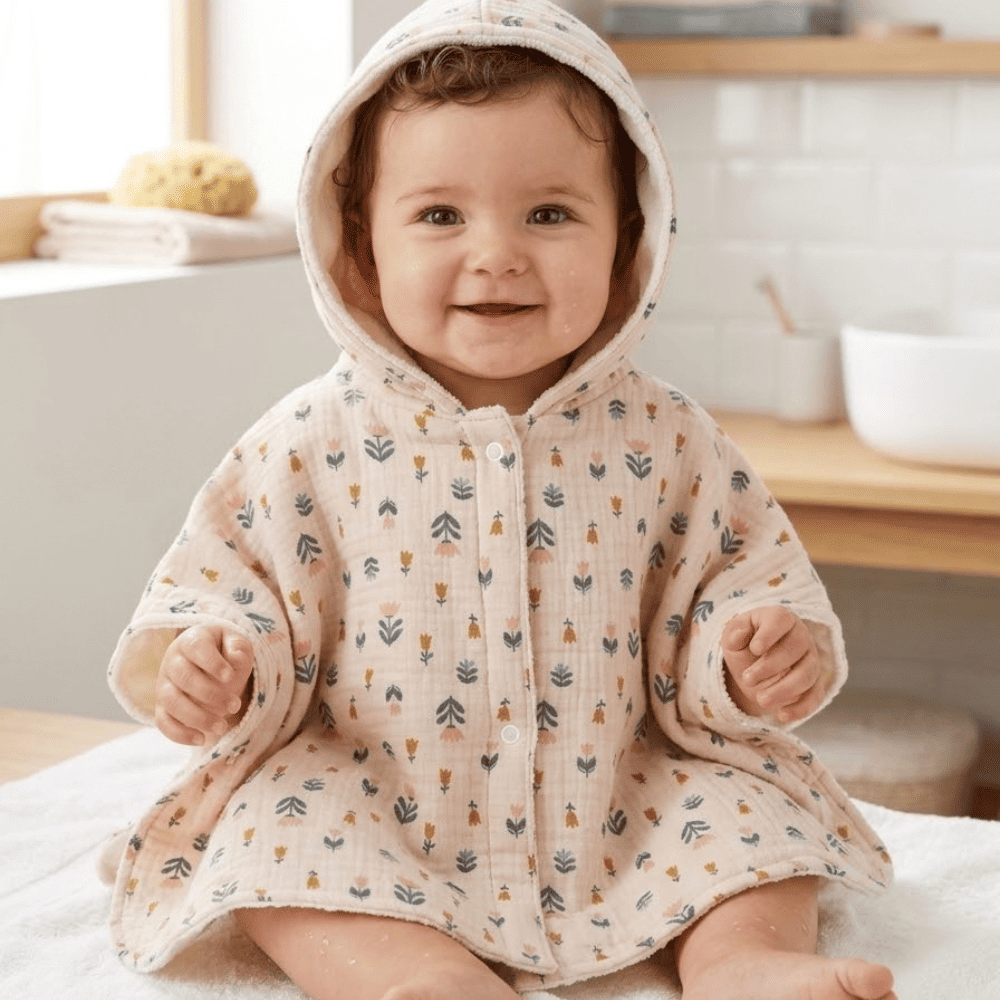 Bébé portant le poncho de bain à capuche Agathe en gaze de coton imprimé floral beige rose et jaune moutarde