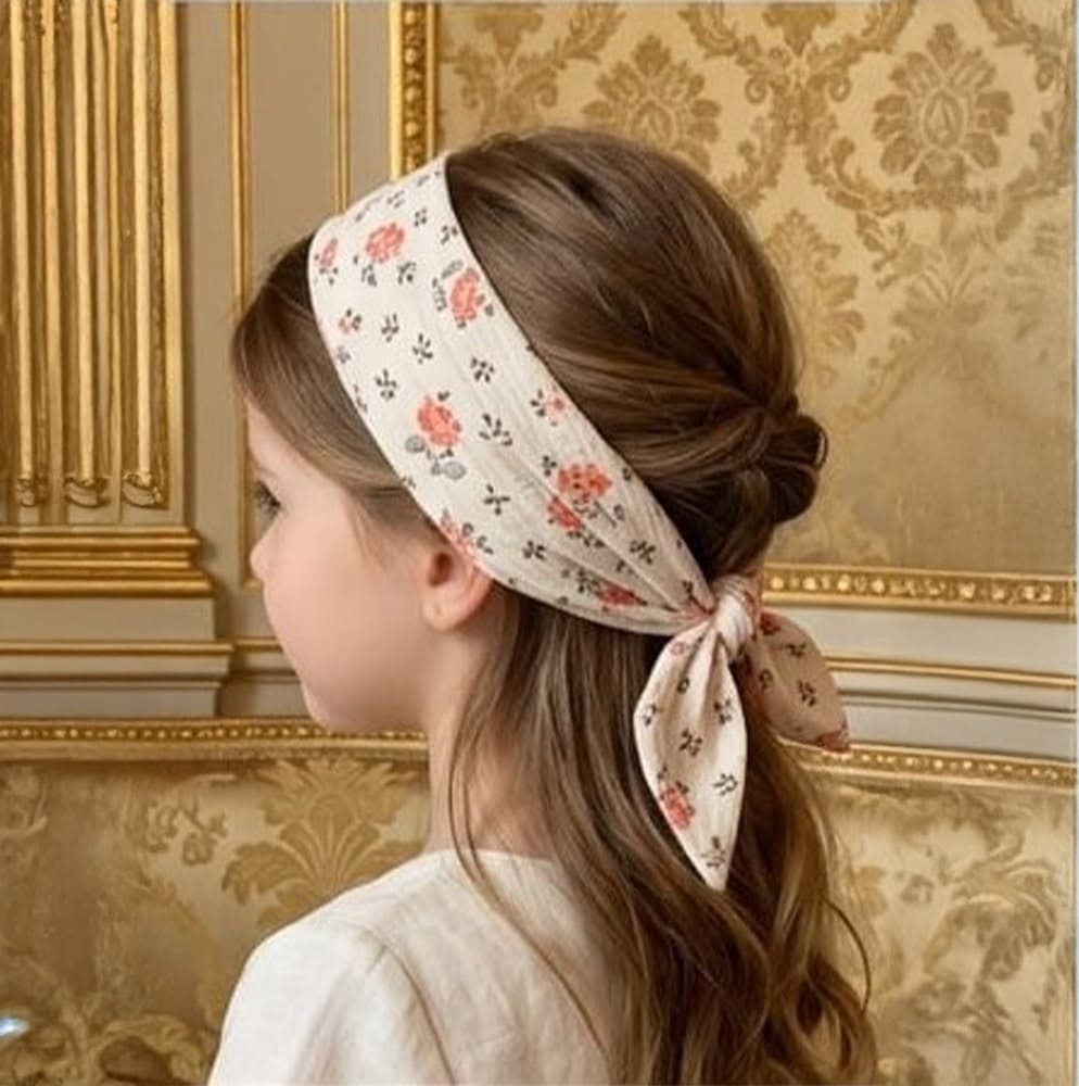 Petite fille portant le foulard Anna en bandana dans les cheveux, à fleurs roses et feuilles vertes