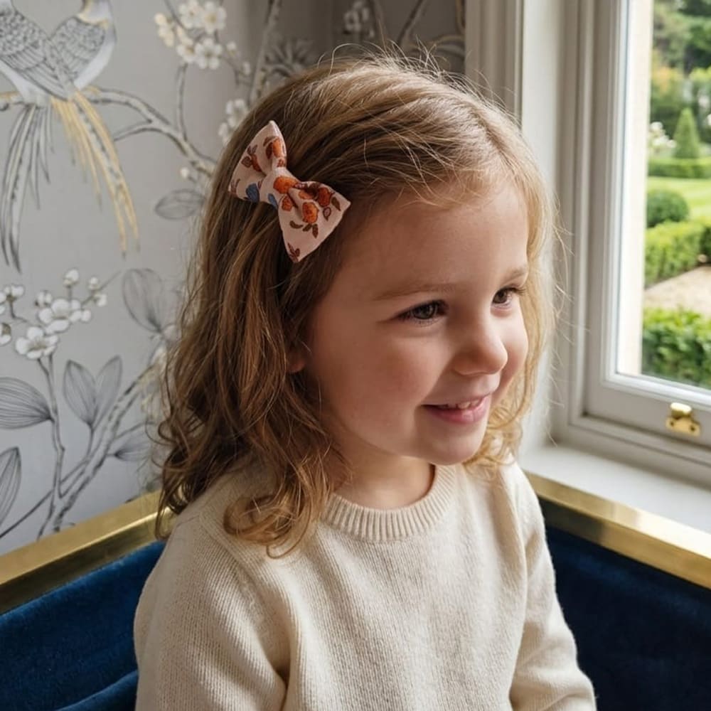 Petite fille qui a la barrette Emy dans les cheveux, à motifs fleuris oranges et marrons