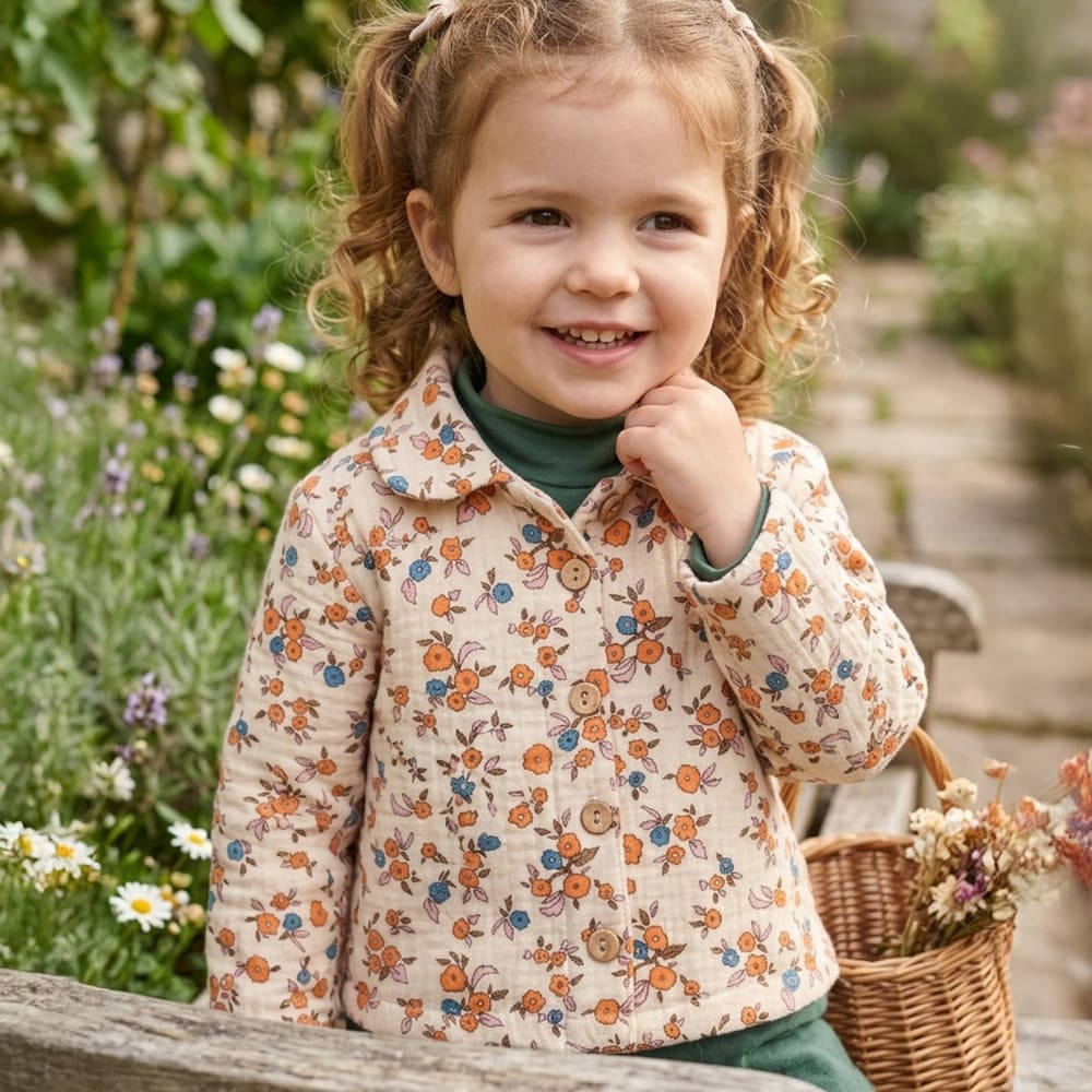 Petite fille portant la blouse Emy, à motifs fleuris bleus, roses et oranges
