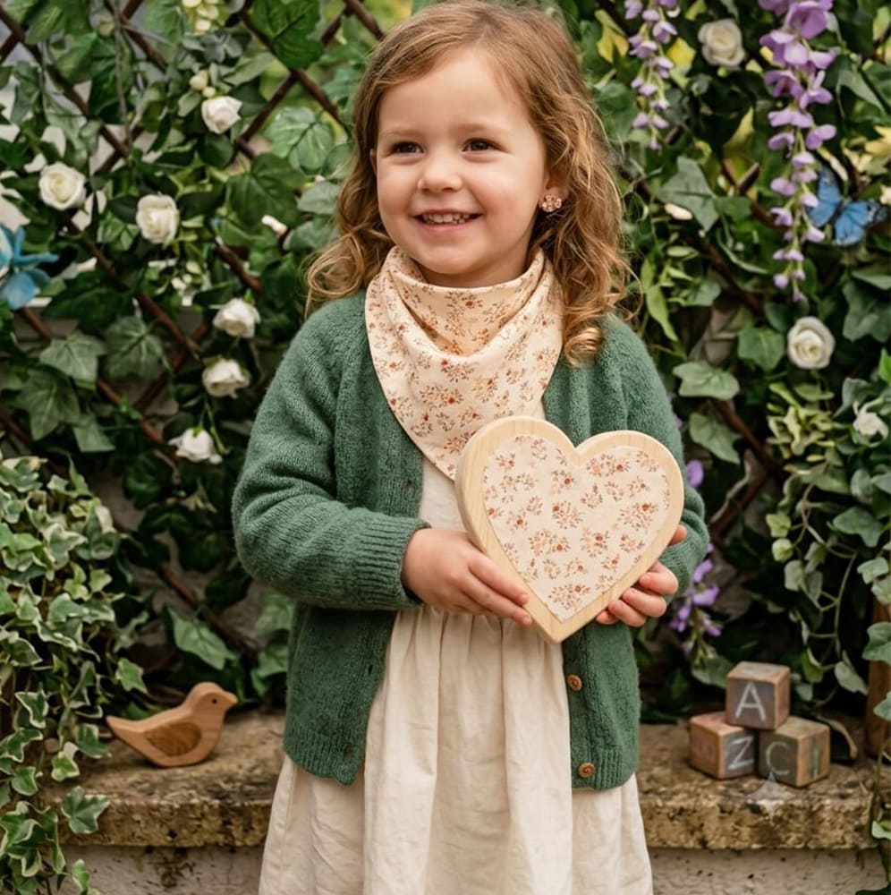 Petite fille portant le foulard Aby, beige avec des motifs rouges