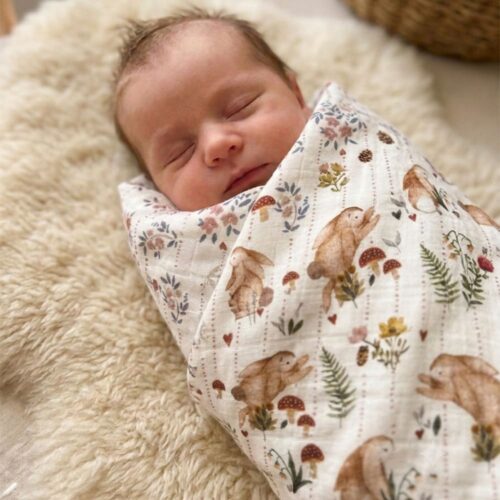 maxi-lange-alice Bébé emmailloté dans le maxi lange Alice, à motifs colorés de lapin dans la forêt