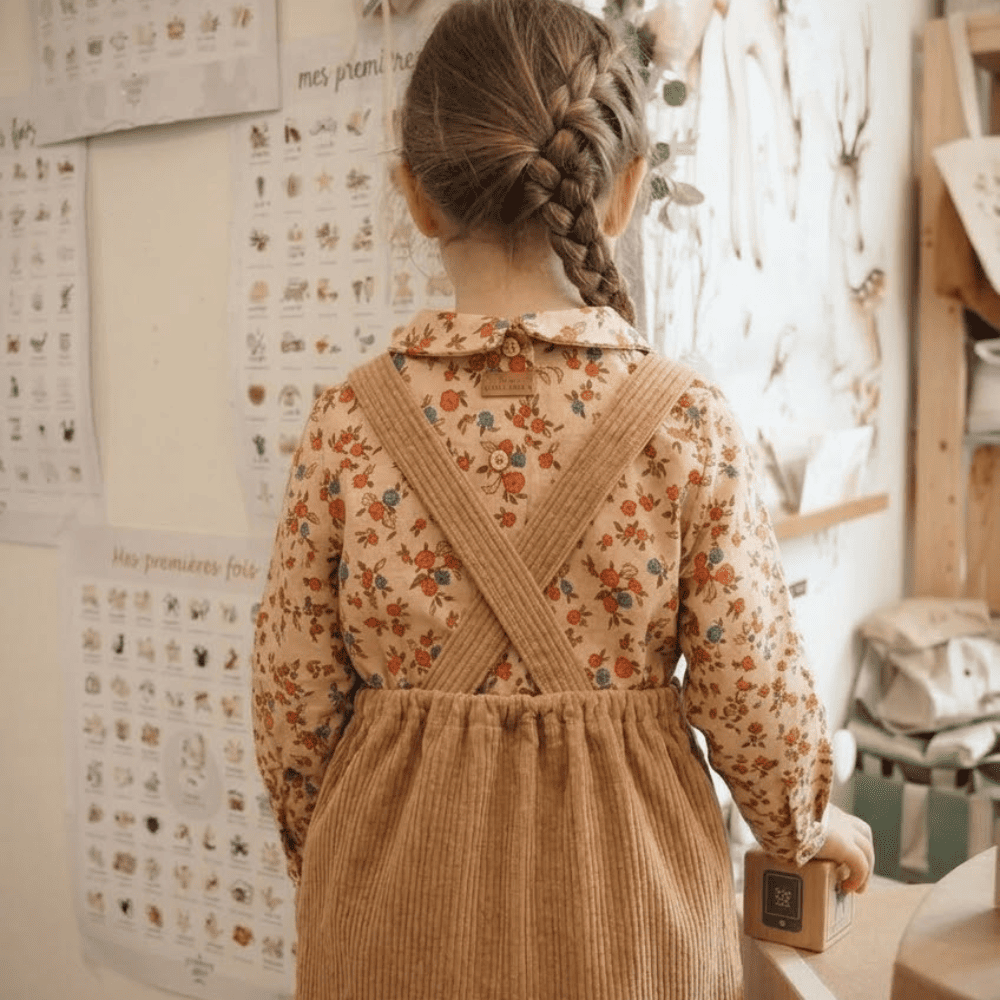 Pettie fille de dos portant la robe en velours Emmy, avec les bretelles croisées visibles